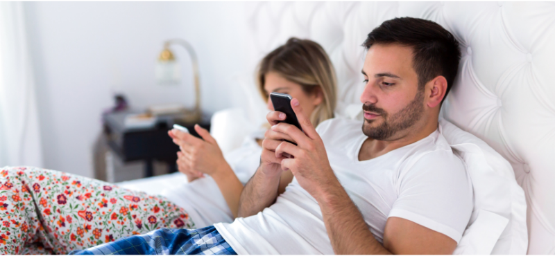 couple in bed texting