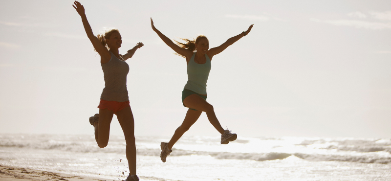 women jumping at beach